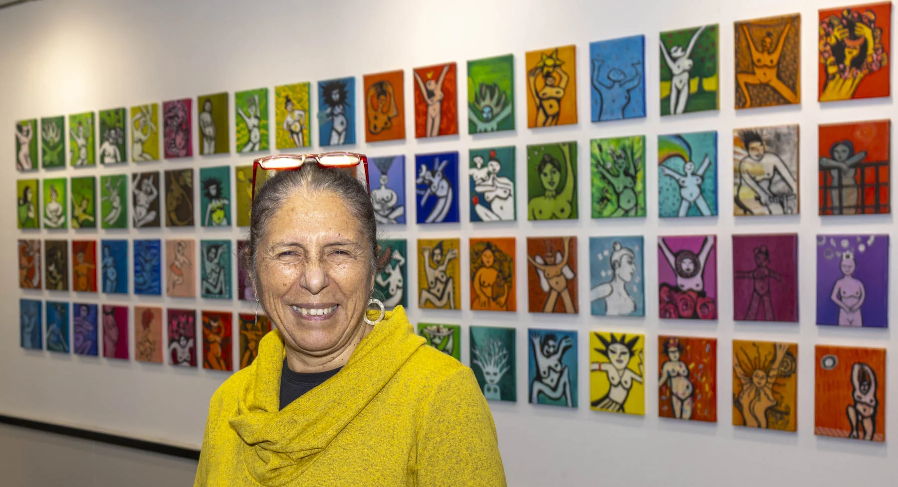 Porträtaufnahme von Carmen Luna, lachend, vor der Ausstellungswand